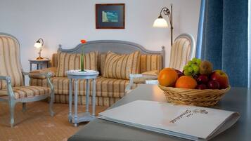 Una sala de estar acogedora con un sofá, dos sillones, una mesita y una cesta de frutas.