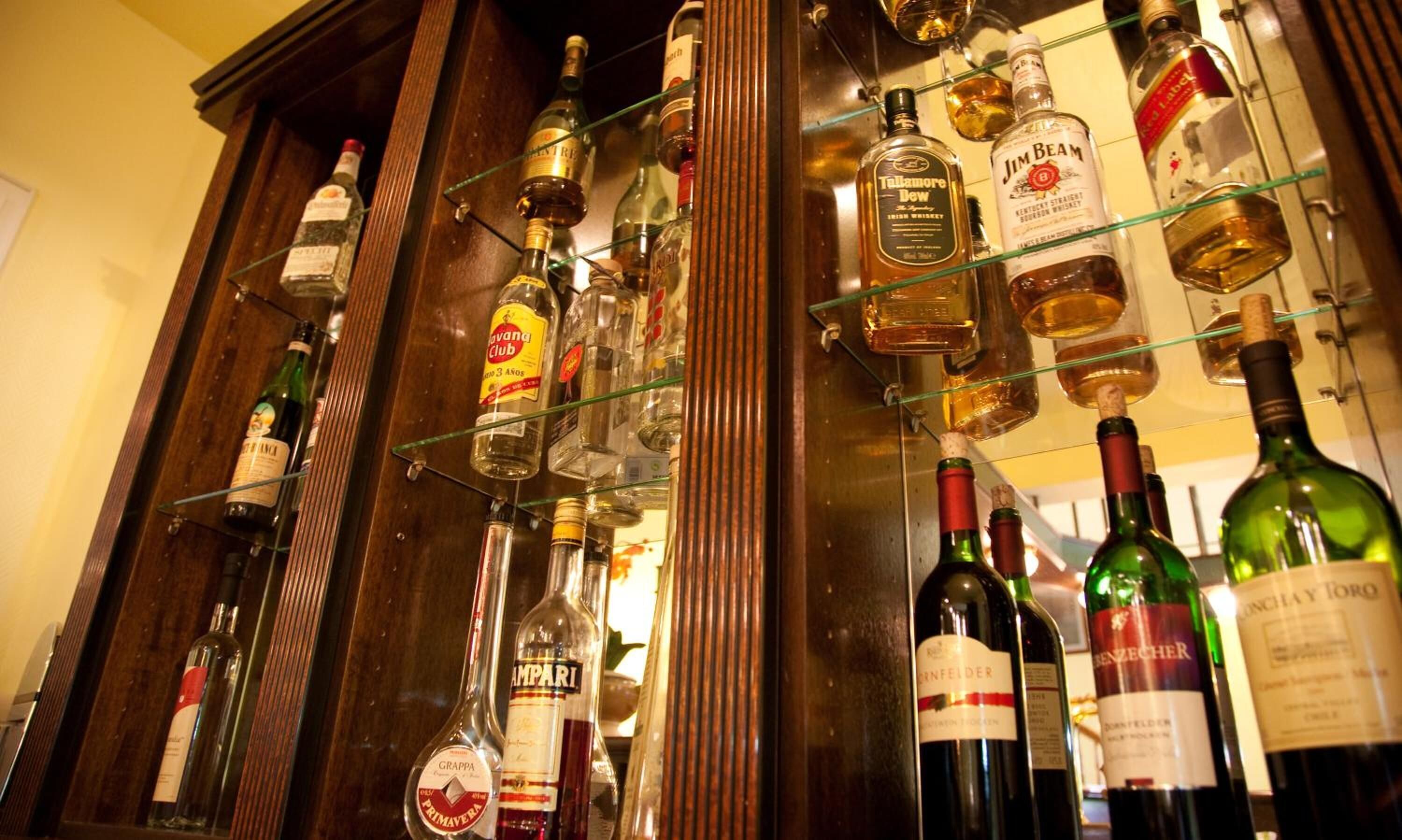 Variedad de botellas de licor exhibidas en estanterías en un bar.