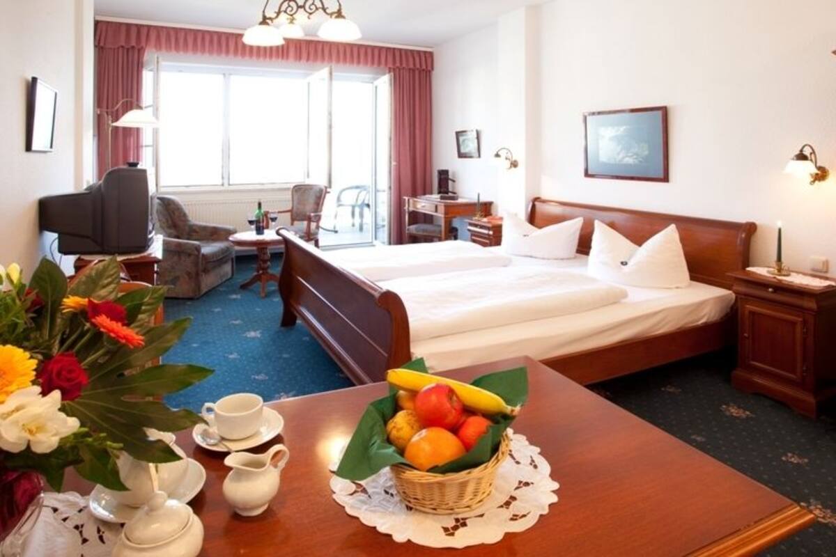A hotel room with a bed, bedside table, lamp, and a fruit basket on the nightstand.