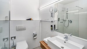 A modern bathroom with a glass shower enclosure, a white sink, and a wooden vanity. - Sure Hotel by Best Western Rhoen Garden (Poppenhausen)