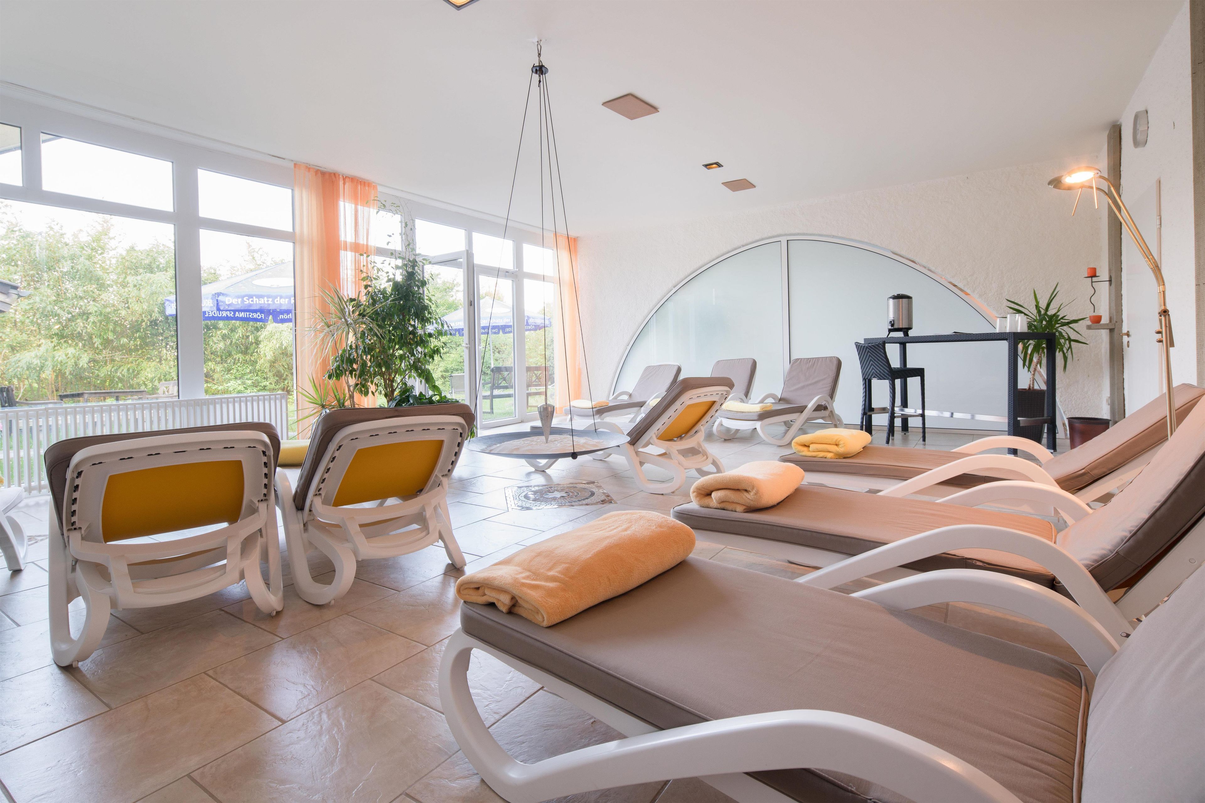 A sunlit room with reclining chairs, a table, and a view of greenery outside.