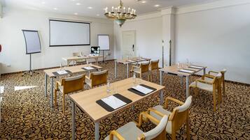 A conference room with multiple tables, chairs, a projector screen, and a whiteboard.
