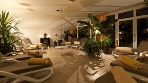 A sunlit lounge area with reclining chairs, a coffee table, and potted plants. - Sure Hotel by Best Western Rhoen Garden (Poppenhausen)