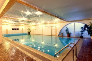 Una piscina interior con agua cristalina, paredes de azulejos y techo de madera.