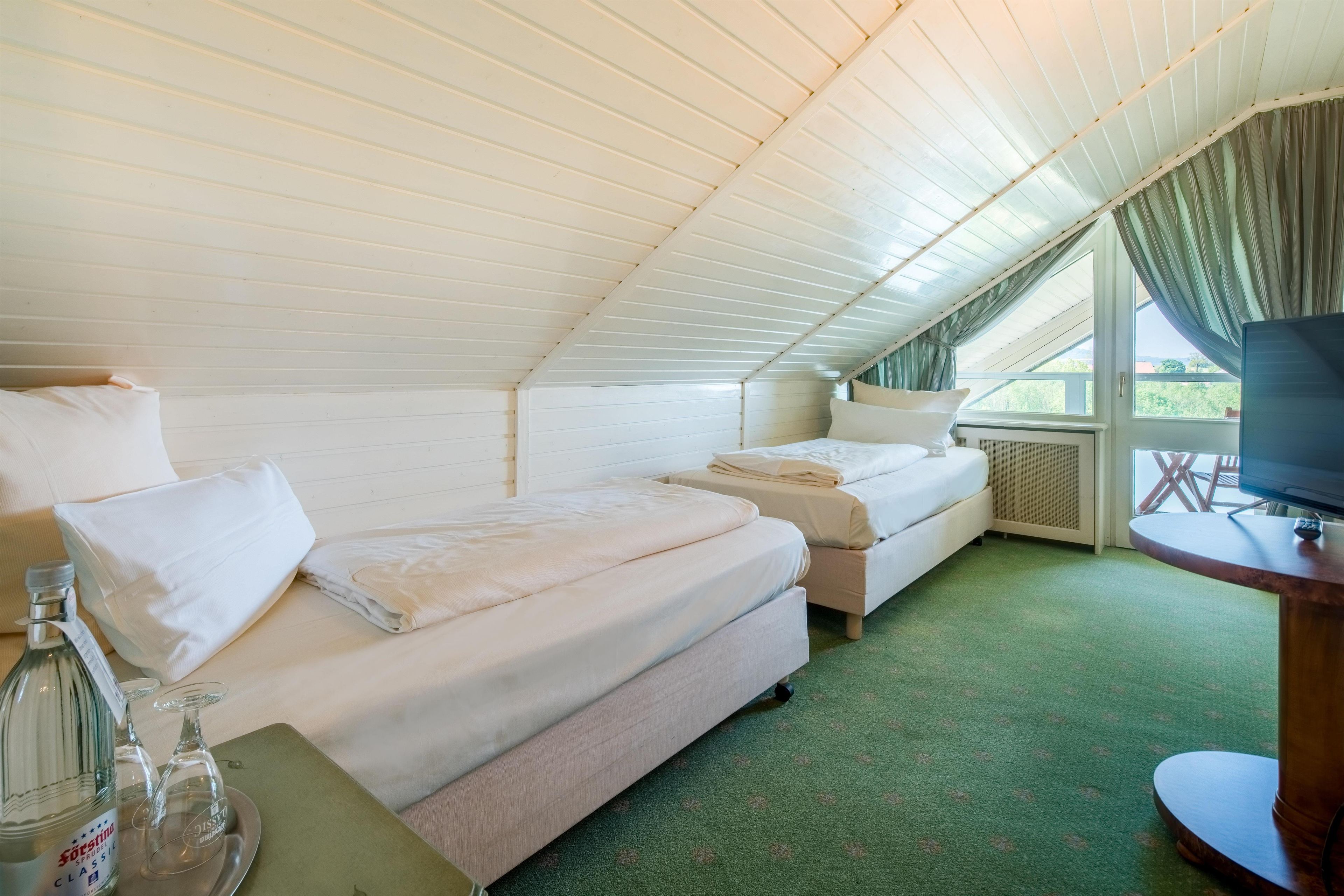 A room with two beds, a television, and a table with a bottle and glasses.