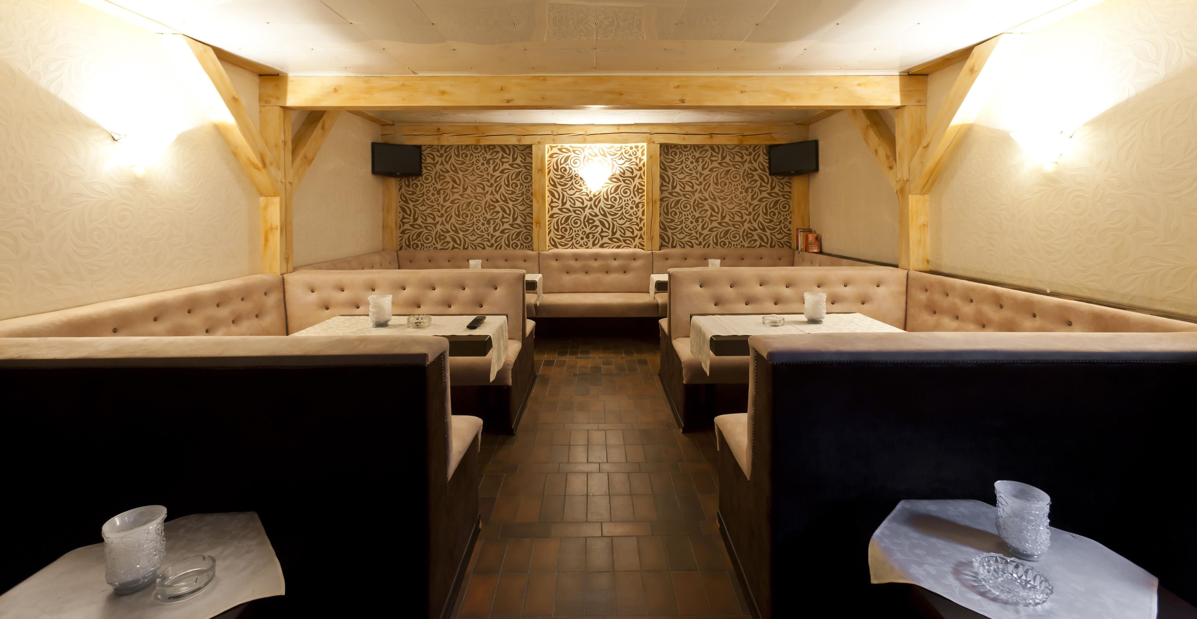 Un restaurante con cabinas y mesas, papel tapiz estampado y piso de baldosas.