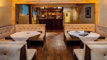 A cozy restaurant with two booths and a bar in the background.