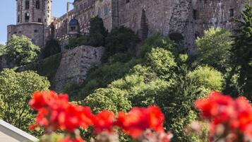Eine historische Burg mit einem markanten Turm und befestigten Mauern, umgeben von üppiger Vegetation.