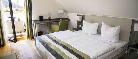 Habitación de hotel con cama, escritorio, silla y vistas al exterior.