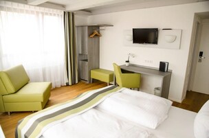 Una habitación de hotel con cama, escritorio, silla, televisión y armario.
