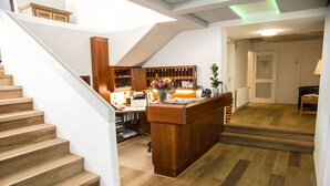 A spacious hallway with a wooden staircase, a reception desk, and a kitchen area. - Hotel Am Schloss (Heidelberg)