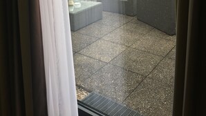 A view through a window of a patio area with outdoor furniture and a view of buildings in the background. - Hotel Am Schloss (Heidelberg)