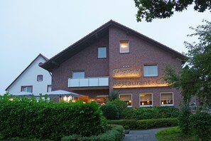 A Posthotel Restaurant & Car rental building with a brick facade, large windows, and outdoor seating area. - Hünerbein's Posthotel (Bissendorf)