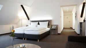 A modern hotel room with a large bed, bedside tables, a nightstand, a desk, and a chair. - Hünerbein's Posthotel (Bissendorf)