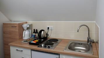 A compact kitchenette with a coffee maker, kettle, and stove.
