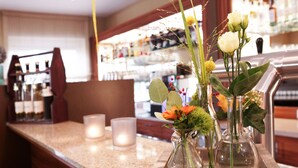 A bar area with a counter, candles, and vases with flowers. - Hünerbein's Posthotel (Bissendorf)