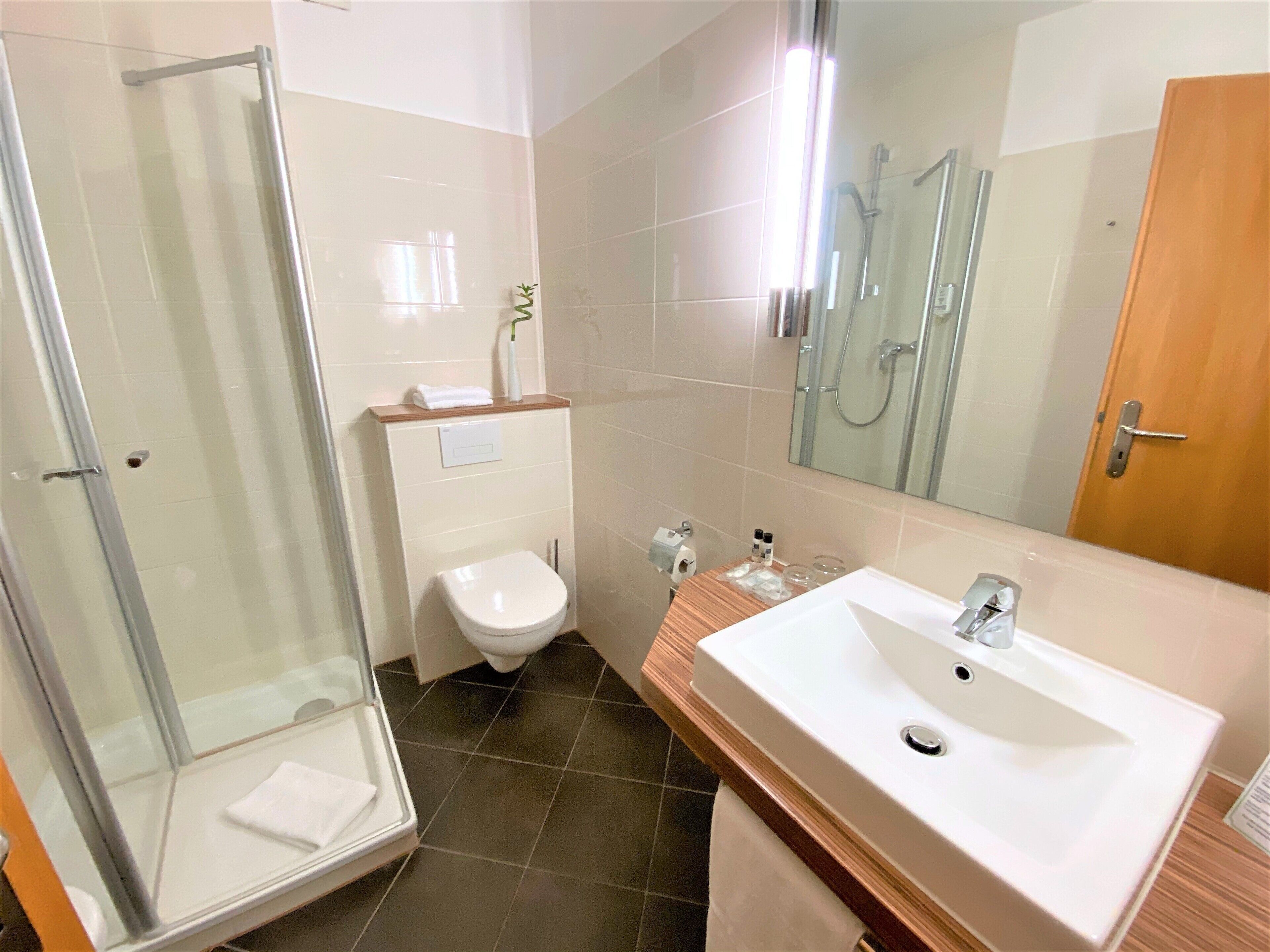 Un baño moderno con cabina de ducha de vidrio, inodoro y lavabo con espejo.