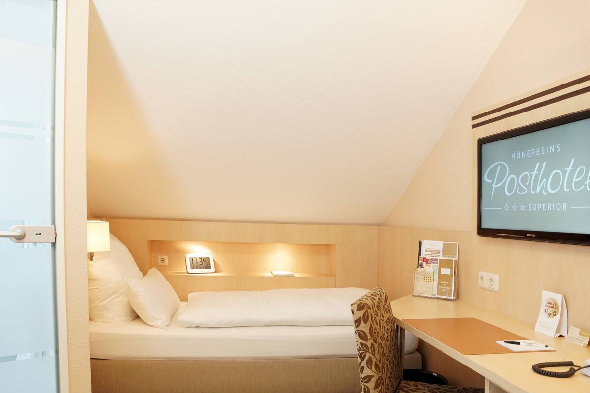 Habitación de hotel con cama, escritorio, silla, televisor y cartel en la pared.