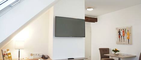 Een moderne kamer met een bureau, stoelen, een flatscreen-tv, een schilderij en een raam met uitzicht.