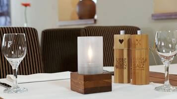 Uma mesa de jantar com uma vela, dois recipientes de madeira e uma taça de vinho.