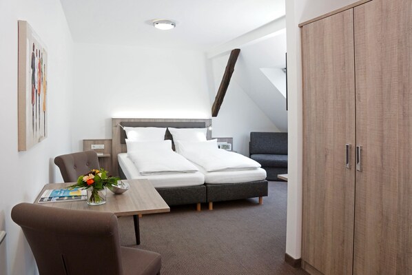 A modern hotel room with a bed, a desk, a chair, a wardrobe, and a painting on the wall. - Hünerbein's Posthotel (Bissendorf)