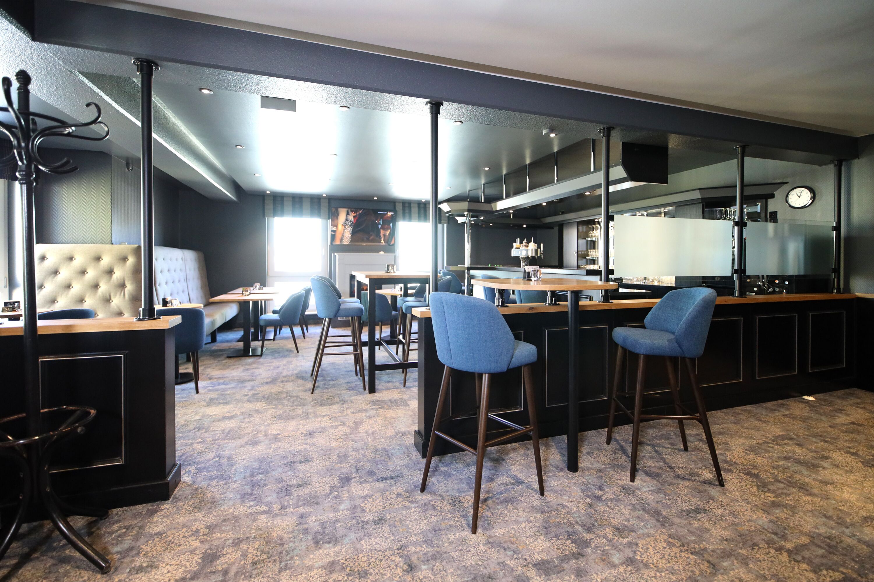 A modern bar area with high stools, a bar counter, and a seating area with tables and chairs.