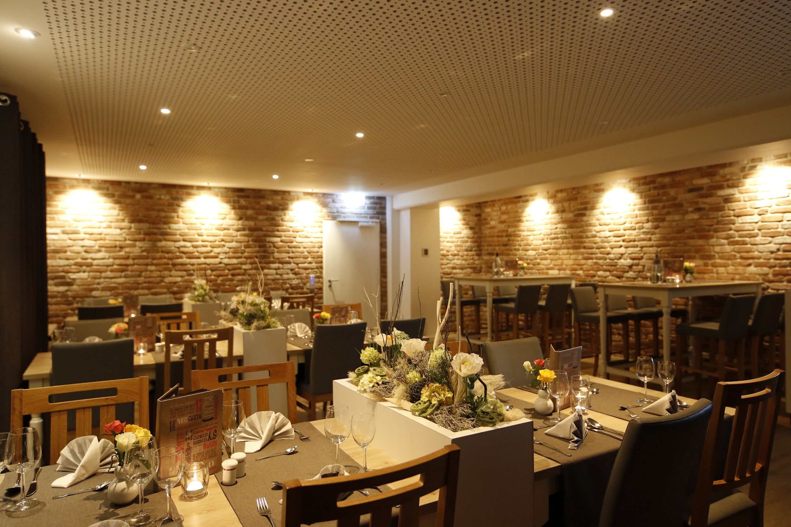Ein Restaurant mit Backsteinwänden, Holztischen und -stühlen.