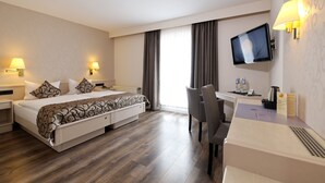 Una habitación de hotel con cama, escritorio, silla, televisor y lámparas de noche.