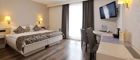 Una habitación de hotel con cama, escritorio, silla, televisor y lámparas de noche.