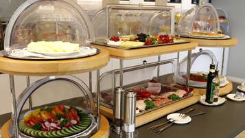 Ein Buffet mit verschiedenen Speisen unter Glasschalen, darunter Käse, Obst und Fleisch.