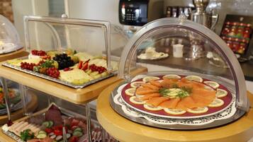 Un bufé con diversas opciones de comida, incluyendo salmón ahumado, frutas y quesos.