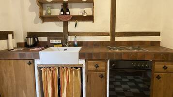 Una cocina con un lavamanos blanco, armarios de madera, una estufa y un tendedero con toallas.
