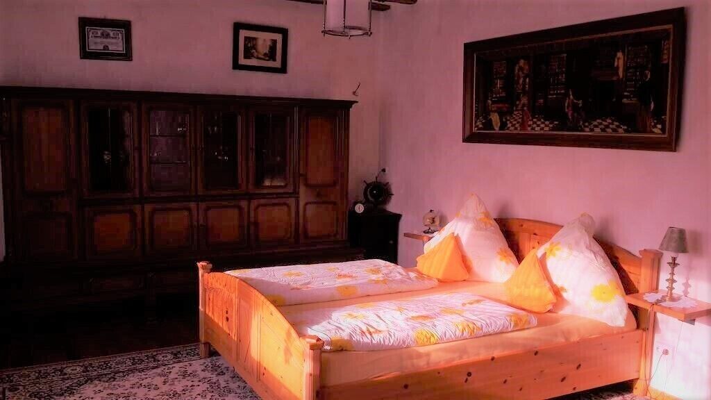 A bedroom with a wooden bed, a nightstand, a lamp, and a painting on the wall.