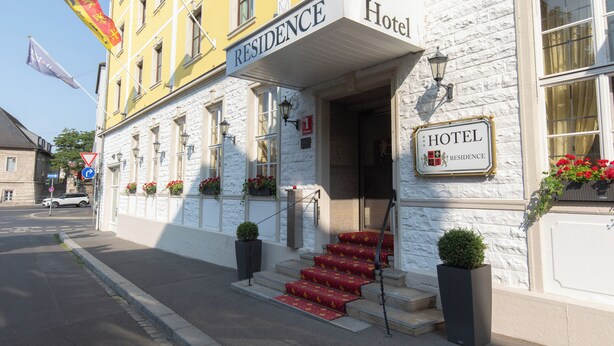 Entrada de un hotel con un letrero que dice "RESIDENCE Hotel" y una escalera que lleva a la puerta.