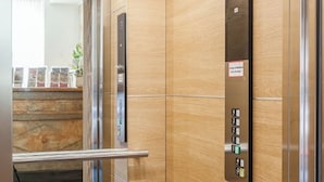 Un ascensor con interior de madera y panel de control metálico.