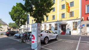 Un hotel con fachada blanca, entrada roja y una bandera.
