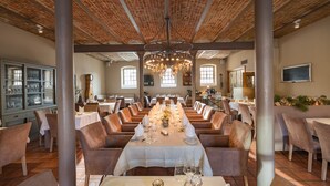 Un restaurante con una mesa larga preparada para una comida, rodeada de sillas y un techo de ladrillo.