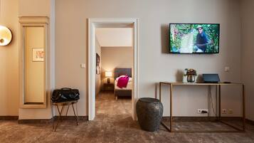 A hotel room with a bed, a TV, a desk, and a suitcase on a stand.