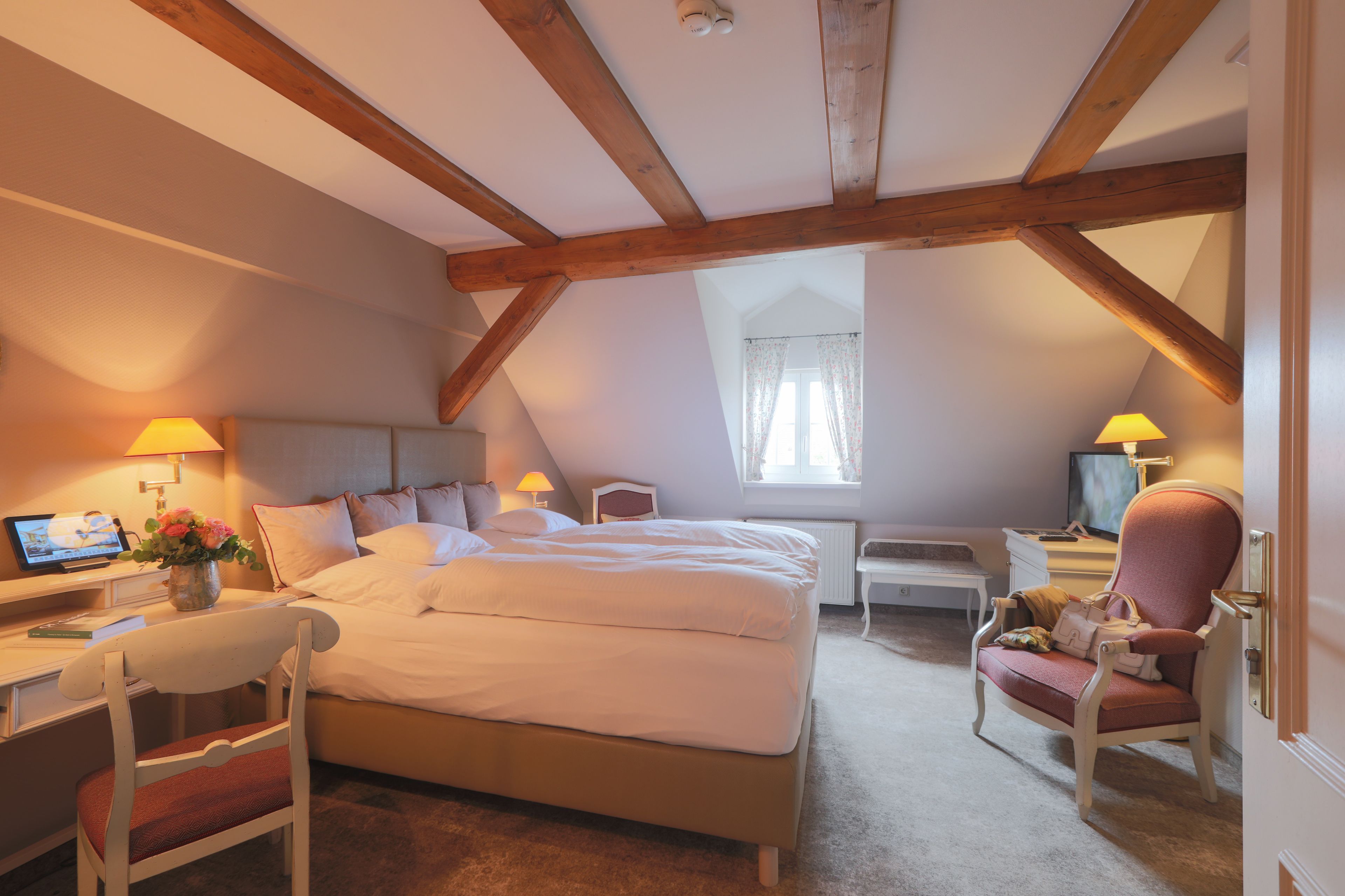 Une chambre à coucher avec un grand lit, un bureau avec un ordinateur, une chaise et un téléviseur.