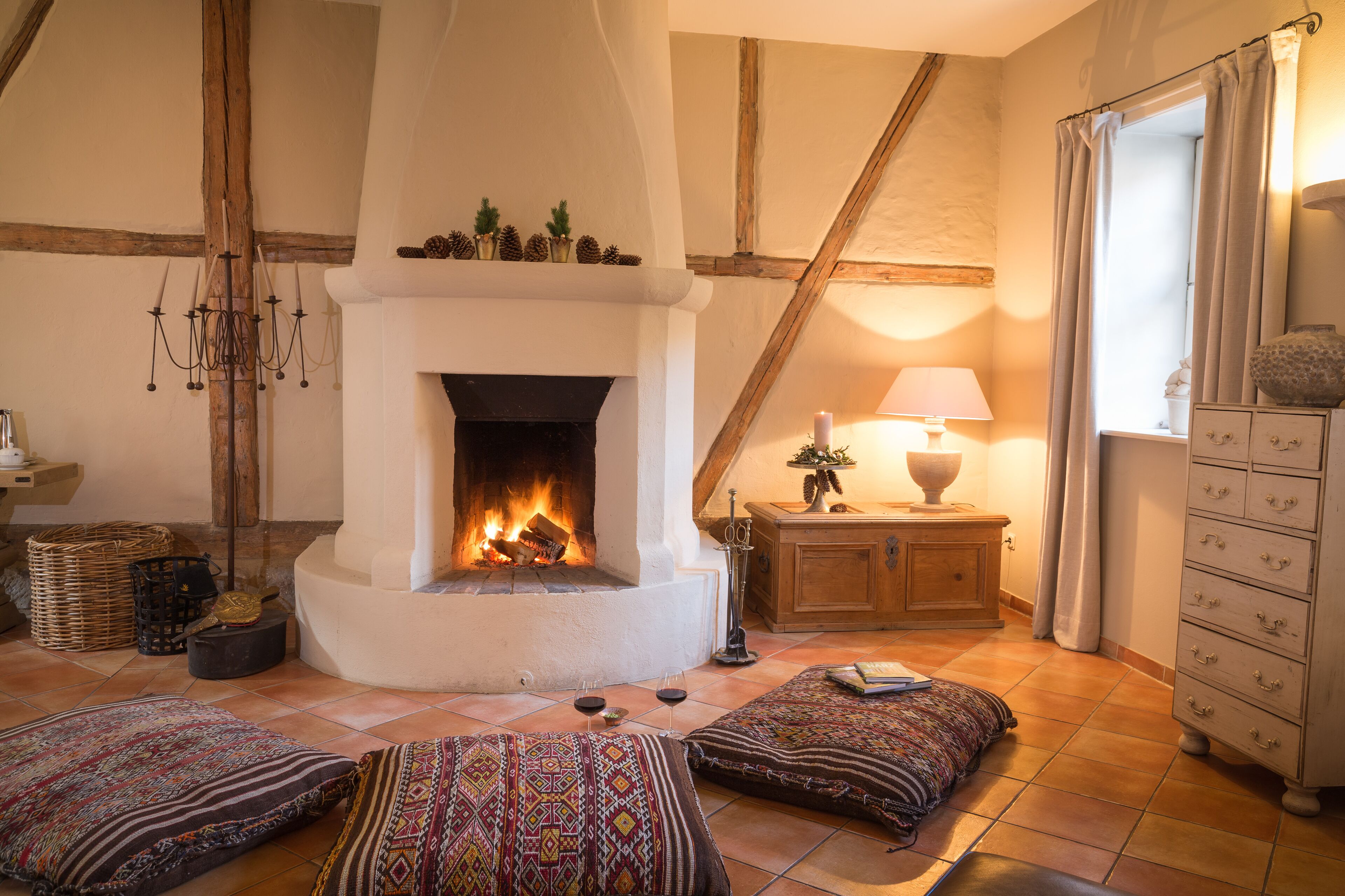 Una sala acogedora con chimenea, cojines estampados, un aparador de madera y una lámpara.