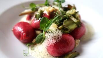 A plate with a dish of radishes, greens, and a creamy sauce.