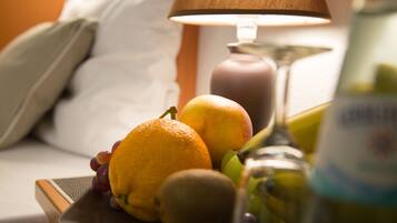A fruit plate on a bedside table with a lamp and a bottle in the background.