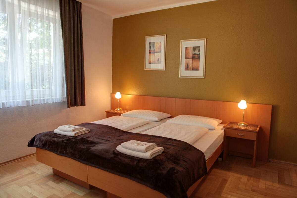 Een hotelkamer met een groot bed, twee nachtkastjes en twee wandlampen.