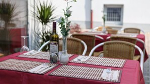 A table set for dining with a red tablecloth, white placemats, and a bottle of wine. - Garni Hotel Rödelheimer Hof (Frankfurt)
