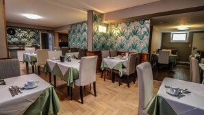 A dining area with tables set for two, featuring green tablecloths and white chairs. - Garni Hotel Rödelheimer Hof (Frankfurt)