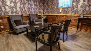 A room with a wooden floor, floral wallpaper, a sofa, a table, and chairs. - Garni Hotel Rödelheimer Hof (Frankfurt)