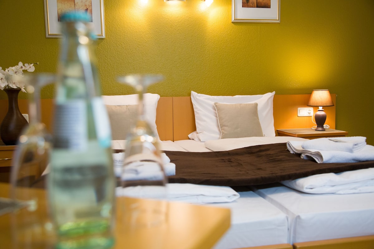 Een hotelkamer met een bed, een nachtkastje met een lamp en een vaas met bloemen.