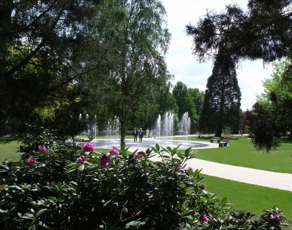 A park with a fountain, green lawns, and trees. - Kishotel Am Kurpark (Bad Soden-Salmuenster)