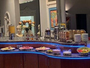 A buffet setup with various food items, a statue, and a mirror. - Gästehaus Kral (Erlangen)