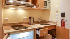 A compact kitchen with a built-in oven, microwave, and a sink. - Gästehaus Kral (Erlangen)